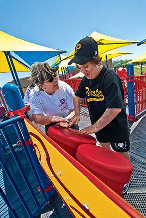 A young person plays the bongo drums on the bongo panel, which is a component that promotes playground accessibility. 